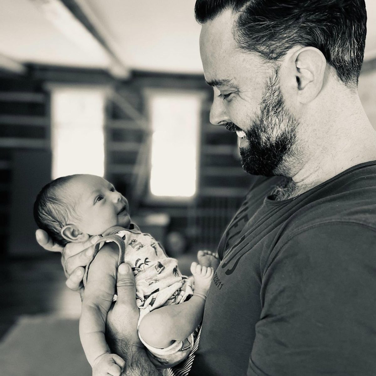 Dave Bussell smiling at his newborn son, held in his arms